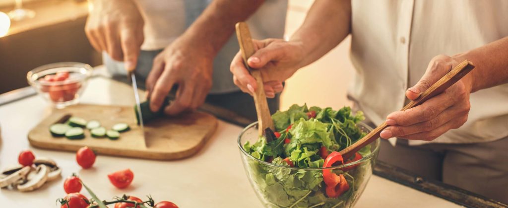 husband and wife making a salad at their kitchen counter